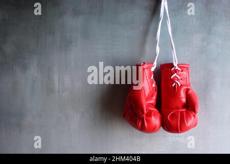 Guanti da boxe rossi appesi alla parete con spazio per la copia del testo. Concetto di pensionamento Foto Stock