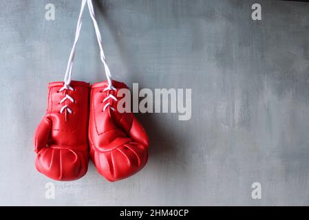 Guanti da boxe rossi appesi alla parete con spazio per la copia del testo. Concetto di pensionamento Foto Stock