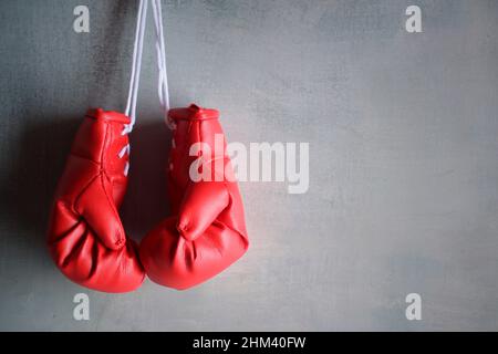 Guanti da boxe rossi appesi alla parete con spazio per la copia del testo. Concetto di pensionamento Foto Stock