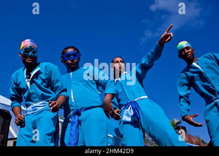 Quattro giovani uomini in abiti blu abbinati celebrano il carnevale alle Seychelles. Foto Stock