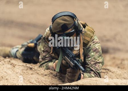 Marine Soldier in MTP uniforme che posa sulla sabbia e mira a Target. Foto di alta qualità Foto Stock