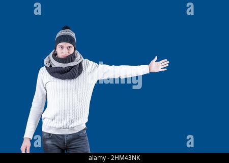 Un uomo bianco con un cappello e una sciarpa allungò la mano a lato. Mano distesa e movimento del palmo aperto Foto Stock