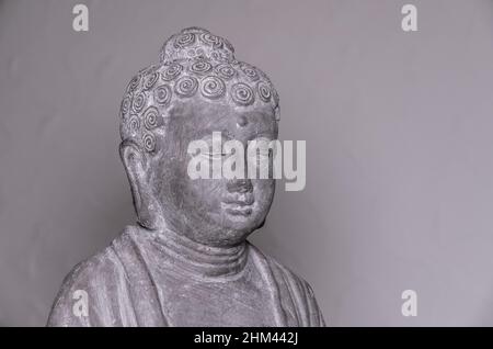 Statua del Buddha di Siddharha Gautama in pietra grigia come decorazione interna, vista ravvicinata del ritratto Foto Stock