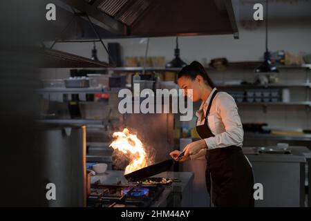Chef professionista che prepara il pasto, flambing al coperto nella cucina del ristorante. Foto Stock