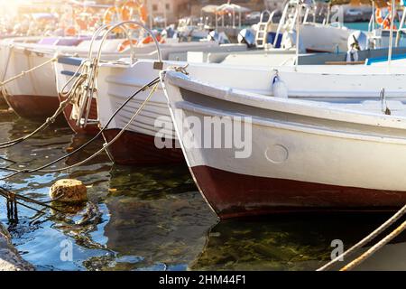 Fila di molte piccole vecchie navi di legno colorato brillante pesca ormeggiate al villaggio di pescatori marina baia acqua chiara in luminoso giorno di sole. Porto marittimo Foto Stock
