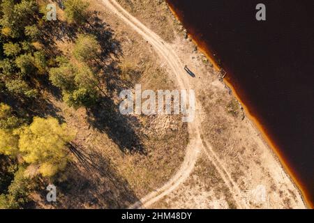 Coppia in piedi vicino fiume colpo dall'alto. Uomo e donna vicino alla riva del fiume con lunghe ombre Foto Stock