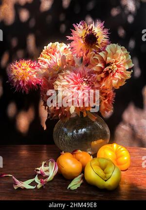 Bouquet romantico con dahlias e pomodori nel bagliore della luce del sole. Mazzi estivi di fiori agricoli all'aperto nel giardino. Floristics - arte del fiore Foto Stock