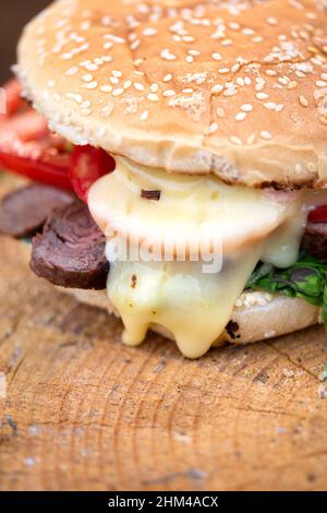 Primo piano di un gustoso hamburger. Formaggio fuso scorrevole. Profondità di campo poco profonda Foto Stock