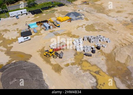 Area di preparazione della vista aerea per cantiere con escavatore per macchinari per trattori pesanti e tubi in calcestruzzo impilati su cui costruire sistemi di drenaggio Foto Stock