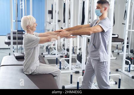 Terapista manuale che mette le sue palme sopra le mani del pensionato Foto Stock