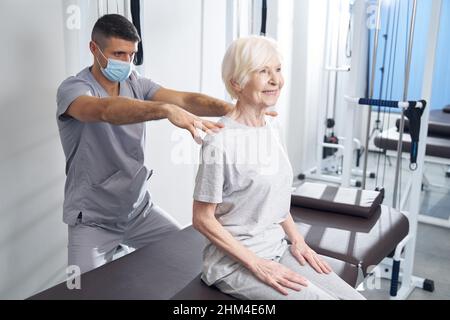 Fisioterapista che dà il massaggio alle spalle della signora felice Foto Stock