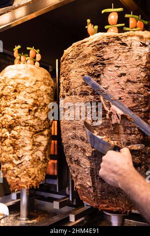 Chef taglio di carne di agnello alla griglia da spit rotante facendo tradizionale turco Street food Doner Kebab (Shawarma o Gyros in altre culture) a Istanbul Foto Stock