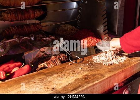 Lo chef trita gli intestini di agnello alla griglia facendo il tradizionale cibo turco di strada Kokorech (Kokorec) a Istanbul, Turchia Foto Stock