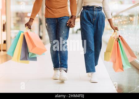Primo piano di coppia nera a piedi con borse shopping Foto Stock