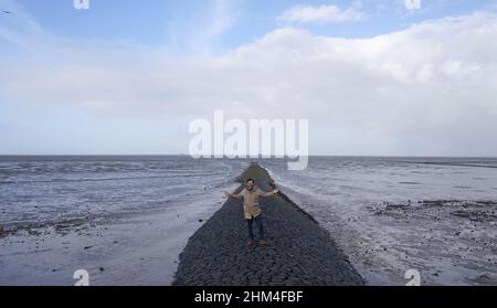 07 febbraio 2022, Schleswig-Holstein, Nordstrand: Jan Philipp Albrecht (Bündnis 90/Die Grünen), ministro della transizione energetica, dell'agricoltura, dell'ambiente, della natura e della digitalizzazione, si trova su un groyne nel Mare di Wadden, sulla costa del Mare del Nord, durante un briefing mediatico sulla strategia di protezione costiera. In considerazione del previsto aumento dei livelli del mare e di forti picchi di tempeste, il proseguimento del programma di rafforzamento della diga riveste particolare importanza per lo stato dello Schleswig-Holstein. Secondo il ministero, circa un quarto della superficie dello Schleswig-Holstein è potenzialmente a rischio di tempesta su Foto Stock