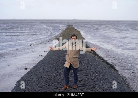 07 febbraio 2022, Schleswig-Holstein, Nordstrand: Jan Philipp Albrecht (Bündnis 90/Die Grünen), ministro della transizione energetica, dell'agricoltura, dell'ambiente, della natura e della digitalizzazione, si trova su un groyne nel Mare di Wadden, sulla costa del Mare del Nord, durante un briefing mediatico sulla strategia di protezione costiera. In considerazione del previsto aumento dei livelli del mare e di forti picchi di tempeste, il proseguimento del programma di rafforzamento della diga riveste particolare importanza per lo stato dello Schleswig-Holstein. Secondo il ministero, circa un quarto della superficie dello Schleswig-Holstein è potenzialmente a rischio di tempesta su Foto Stock