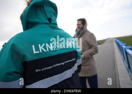 07 febbraio 2022, Schleswig-Holstein, Nordstrand: Jan Philipp Albrecht (Bündnis 90/Die Grünen), ministro della transizione energetica, dell'agricoltura, dell'ambiente, della natura e della digitalizzazione, si trova accanto a Birgit Matelski, direttore dell'Agenzia statale Schleswig-Holstein per la protezione costiera, i parchi nazionali e la conservazione della marina, Durante un briefing dei media sulla strategia di protezione costiera in una diga sulle coste del Mare del Nord. In considerazione del previsto aumento del livello del mare e delle forti tempeste, il proseguimento del programma di rafforzamento della diga riveste particolare importanza per lo stato dello Schleswig-Holstei Foto Stock