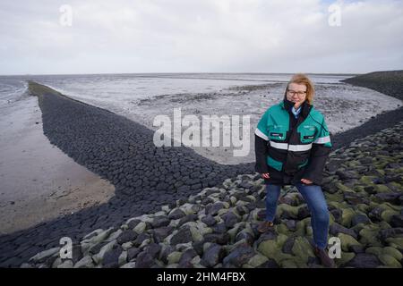 07 febbraio 2022, Schleswig-Holstein, Nordstrand: Birgit Matelski, direttore dell'Ufficio statale Schleswig-Holstein per la protezione costiera, i parchi nazionali e la conservazione della marina, si trova su una diga della costa del Mare del Nord durante un briefing mediatico sulla strategia di protezione della costa. In considerazione del previsto aumento dei livelli del mare e di forti picchi di tempeste, il proseguimento del programma di rafforzamento della diga riveste particolare importanza per lo stato dello Schleswig-Holstein. Secondo il ministero, circa un quarto della superficie dello Schleswig-Holstein è potenzialmente a rischio di picchi di tempesta. Più di 330, 0 Foto Stock