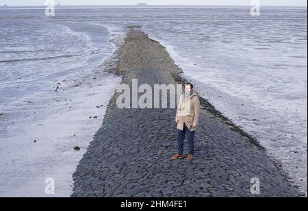 07 febbraio 2022, Schleswig-Holstein, Nordstrand: Jan Philipp Albrecht (Bündnis 90/Die Grünen), ministro della transizione energetica, dell'agricoltura, dell'ambiente, della natura e della digitalizzazione, si trova su un groyne nel Mare di Wadden, sulla costa del Mare del Nord, durante un briefing mediatico sulla strategia di protezione costiera. In considerazione del previsto aumento dei livelli del mare e di forti picchi di tempeste, il proseguimento del programma di rafforzamento della diga riveste particolare importanza per lo stato dello Schleswig-Holstein. Secondo il ministero, circa un quarto della superficie dello Schleswig-Holstein è potenzialmente a rischio di tempesta su Foto Stock