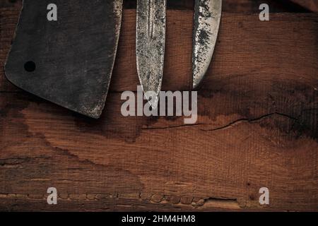 primo piano delle punte dei coltelli e un taglierino su un vecchio tagliere di legno Foto Stock