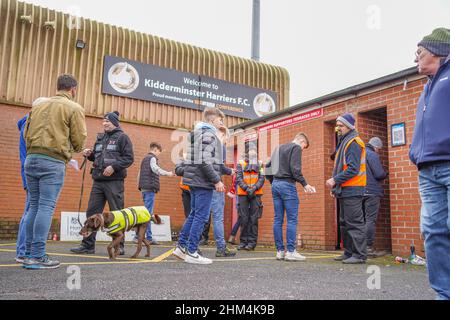 Cane gestore e cane al lavoro che controlla i tifosi in coda ad un ingresso di gioco di calcio britannico. Foto Stock