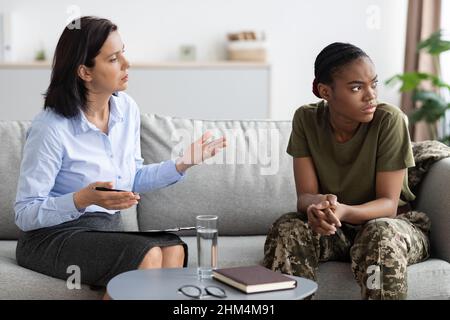 La donna psicoterapista parla con la donna soldato Nera durante la riunione in ufficio Foto Stock