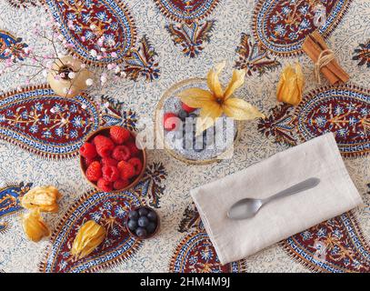 Alto angolo di vista del dessert chia budino con bacche estive, lamponi, mirtilli, banane e physalis. Piatto, vista dall'alto, niente persone. Foto Stock