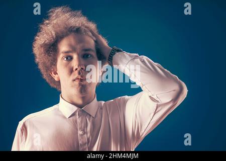 L'uomo frustrato con i capelli ricci guarda tristemente nella macchina fotografica che tiene i suoi capelli con una mano. Concetto di frustrazione e frustrazione. Foto Stock