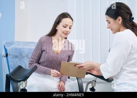 Documento di lettura concentrato della donna in presenza del suo medico Foto Stock