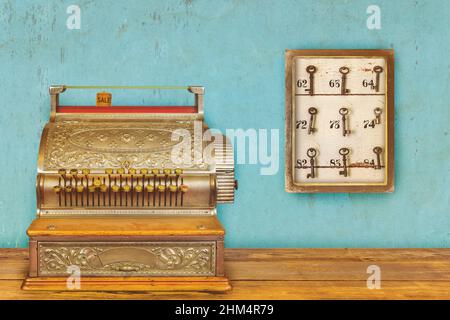 Registratore di cassa e armadietto con chiavi dell'hotel e numeri delle camere su sfondo blu eroso Foto Stock