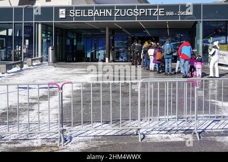 Numerose persone sono in attesa di ingresso alla funivia per la montagna Zugspitze nelle Alpi. Devono mostrare il loro certificato di vaccinazione Covid Foto Stock