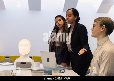 Uomini d'affari che discutono dell'assistente vocale del robot durante la riunione Foto Stock