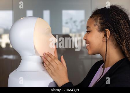 Donna sorridente che guarda l'assistente vocale del robot Foto Stock