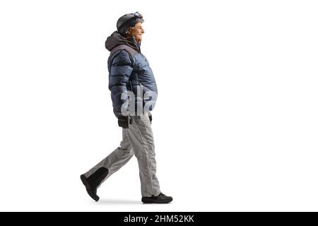 Il profilo completo di un uomo maturo in una giacca invernale e pantaloni che camminano isolati su sfondo bianco Foto Stock