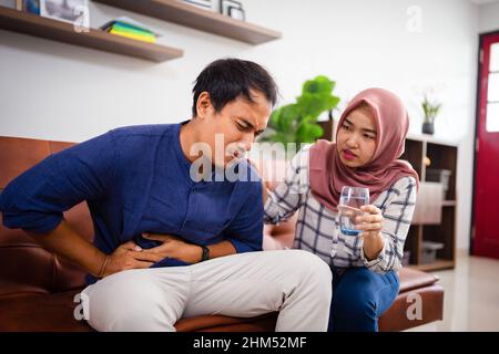 giovane coppia asiatica che beve un bicchiere d'acqua durante il ramadan Foto Stock