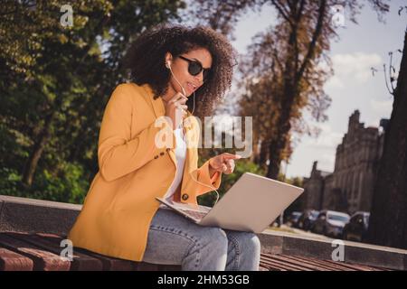 Ritratto di bella ragazza trendy focalizzata passare il tempo in aria fresca utilizzando il portatile ascoltare parlare comunicazione videochiamata all'aperto Foto Stock