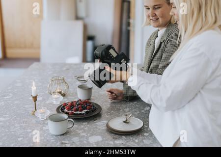 Donne che fotografano cibo in cucina Foto Stock