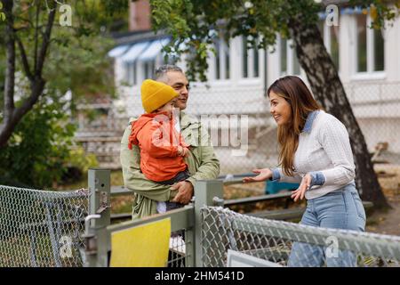 Genitori che parlano insieme, padre che porta il bambino Foto Stock