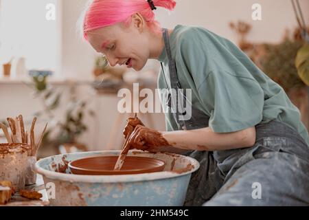 Giovane donna che lavora alla ruota della ceramica in un laboratorio di ceramica Foto Stock