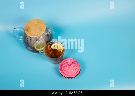 Tazza di tè nero con cupcake rosa su sfondo blu con spazio copia. Foto Stock