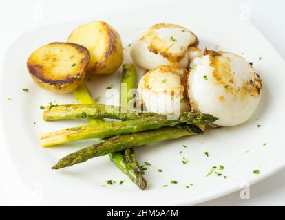 Piatto gourmet di seppie con patate arrosto e asparagi Foto Stock
