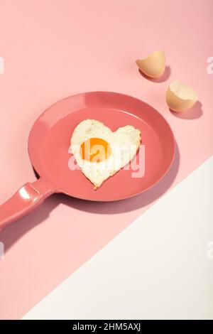 Padella rosa e uovo a forma di cuore. San Valentino Foto Stock
