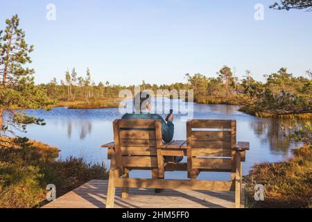Confortevole luogo di riposo, sedie o panchine in legno su terrazza in legno sulla riva di palude, stagno, paesaggio scandinavo Foto Stock