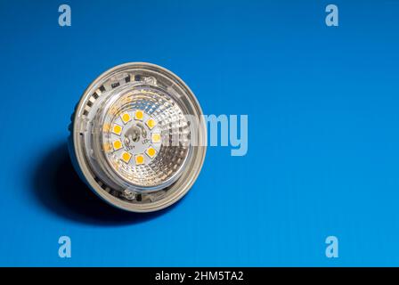 Primo piano di un faretto a LED su una superficie sfocata, fuoco selettivo, lampadina a LED, 5W, alta efficienza energetica, spazio di copia, sfondo blu, orizzontale Foto Stock