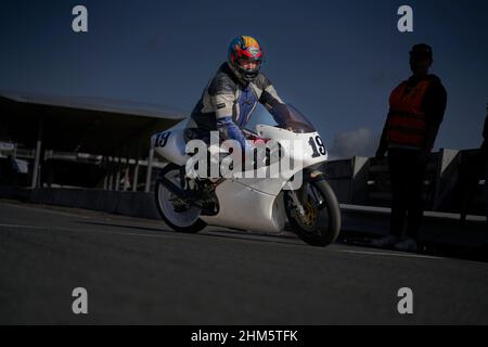 11-05-2021 riga, Lettonia bel pilota uomo con barba e baffi in pelle nera biker giacca e occhiali da sole si siedono su stile classico cafe racer motorc Foto Stock