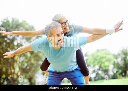 outdoor senior fitness donna uomo lifestyle sport esercizio sano fitness fitness amore divertimento piggyback Foto Stock