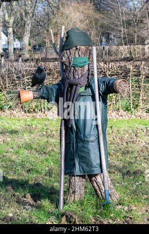 Uno scorecrow in un campo, con un corvo appollaiato Foto Stock