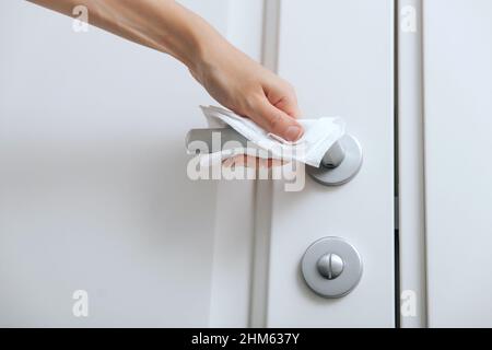 Pulizia delle maniglie delle porte con un panno antisettico e guanti. Sanitizzare la prevenzione delle superfici in ospedale e spazi pubblici contro il virus corona. Donna Foto Stock