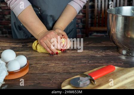 Le donne che preparano la torta di mele deliziosa o la torta grande su sfondo tavola di legno. Impastare l'impasto. Foto Stock