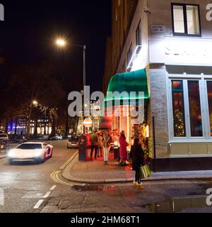 Londra, Greater London, Inghilterra, gennaio 4th 2022: La gente gode di una notte di inverni a Berkeley Square mentre una macchina sportiva guida vicino. Foto Stock